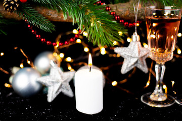 New Year holiday concept. New Year's decor - champagne glasses, New Year's toys, a Christmas tree with decorations, a candle is lit for making a wish.