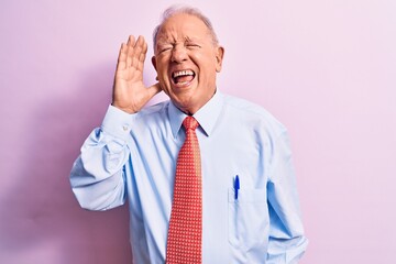 Senior handsome grey-haired businessman wearing elegant tie standing over pink background shouting and screaming loud to side with hand on mouth. Communication concept.