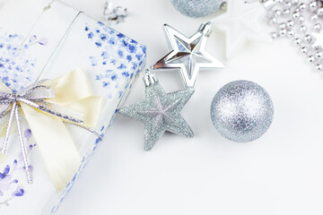 Festive mood, preparation for the holiday. Christmas gift box with festive decor in silvery colors - toys, star, round balls.