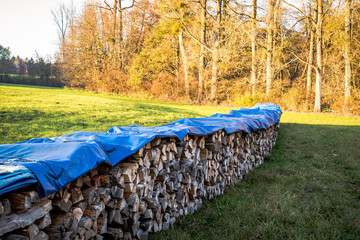 Mit einer Abdeck Plane geschützter Brennholz Stapel
