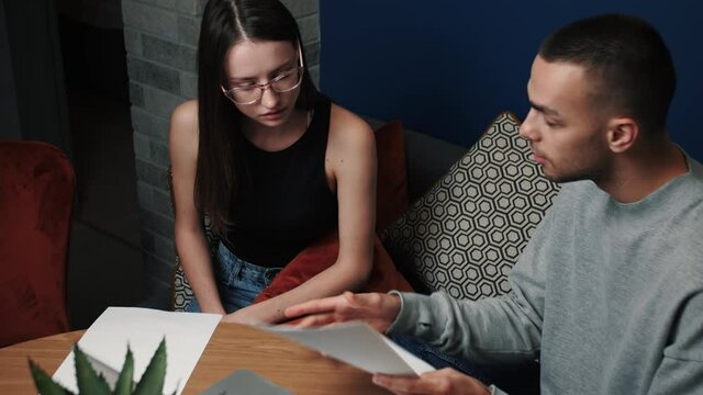 Frustrated young adult man and woman feeling stressed about doing paperwork at home or office. Angry man having financial problems.