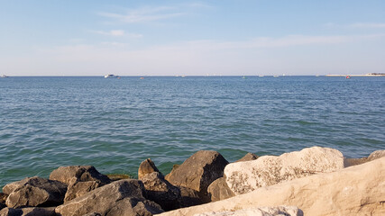 Fototapeta na wymiar Sunny day at the sea with sailboats and ships in the distance. Rimini, Italy