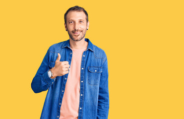 Young handsome man wearing casual clothes doing happy thumbs up gesture with hand. approving expression looking at the camera showing success.