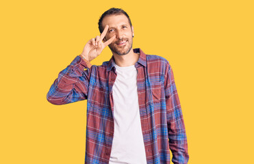 Young handsome man wearing casual clothes doing peace symbol with fingers over face, smiling cheerful showing victory