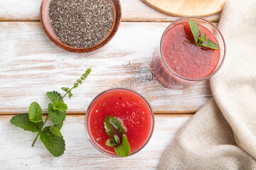 Watermelon juice with chia seeds and mint in glass on a white wooden background with linen textile. Top view,  close up.
