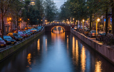 Night view of Amsterdam cityscape with canal, bridge and typical Dutch Houses. Amsterdam, Netherlands.