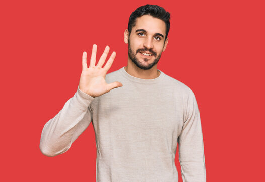 Young hispanic man wearing casual clothes showing and pointing up with fingers number five while smiling confident and happy.