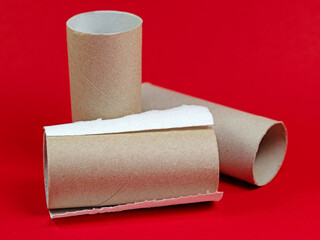 Aufgebrauchte Klopapierrollen vor rotem Hintergrund