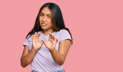 Young latin woman wearing casual clothes disgusted expression, displeased and fearful doing disgust face because aversion reaction. with hands raised