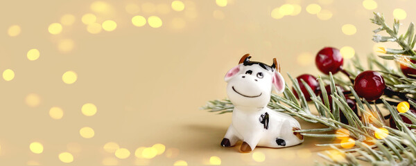 Bull symbol of the new year 2021. Ceramic figurine of small white bull with branches christmas tree on pastel background. Copy space. Banner.
