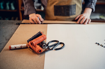 In a family shoe shop a young apprentice works with paper to create a pattern for shoes.