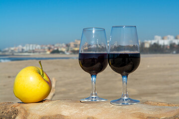 Tasting of different fortified dessert ruby, tawny port wines in glasses on sandy beach with view on waves of Atlantic ocean near Vila Nova de Gaia and city of Porto, Portugal