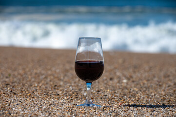 Tasting of different fortified dessert ruby, tawny port wines in glasses on sandy beach with view on waves of Atlantic ocean near Vila Nova de Gaia and city of Porto, Portugal