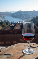 Tasting of different fortified dessert ruby, tawny port wines in glasses with view on Douro river, porto lodges of Vila Nova de Gaia and city of Porto, Portugal