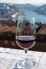 Tasting of different fortified dessert ruby, tawny port wines in glasses with view on Douro river, porto lodges of Vila Nova de Gaia and city of Porto, Portugal