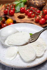 Cheese collection, eating. of white soft Italian cheese mozzarella, served with red cherry tomatoes, fresh basil leaves