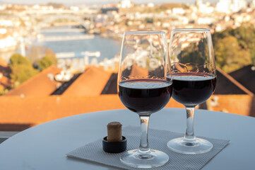 Tasting of different fortified dessert ruby, tawny port wines in glasses with view on Douro river, porto lodges of Vila Nova de Gaia and city of Porto, Portugal