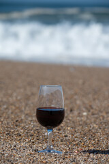 Tasting of different fortified dessert ruby, tawny port wines in glasses on sandy beach with view on waves of Atlantic ocean near Vila Nova de Gaia and city of Porto, Portugal