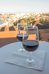 Tasting of different fortified dessert ruby, tawny port wines in glasses with view on Douro river, porto lodges of Vila Nova de Gaia and city of Porto, Portugal