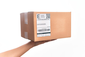 Hand of caucasian young man holding cardboard package showing label with codebar over isolated...
