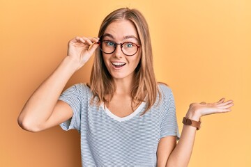 Beautiful blonde woman wearing casual clothes and holding glasses celebrating achievement with...
