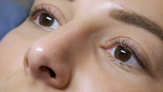The face of a young girl before a modern eyelash lamination procedure in a professional beauty salon before the eyelash curling procedure. Portrait of a woman without makeup with dark lipstick.