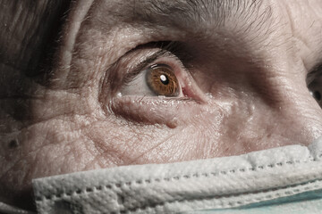 elderly man in face mask in dark room looking with sorrow close view