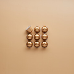 Caffeine, hot drinks and objects concept - close up of golden capsules or pods for coffee mashine on beige background. Top view with space for text. Flat lay..