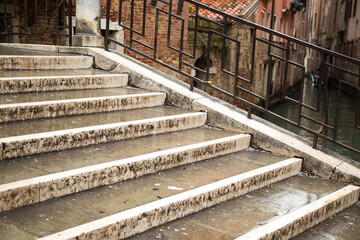 Empty stairs of a marble ladder with metal railings in Venezia. Rainy winter day in italian city. Quarantine for coronavirus in Europe. No people urban landscape. 