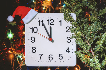 Clock in branches of New Year's fir on black background. Second hand moves in circle of mechanical clock and show Twelve o'clock at  Midnight and eve of Christmas. Holiday concept, time lapse, closeup