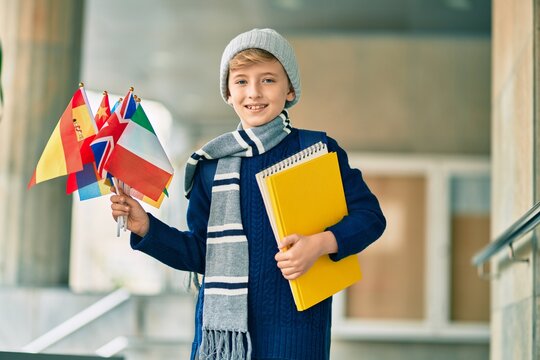 Adorable blond student kid smiling happy holding flags of different countries at the school.