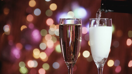 Champagne glass close up on Christmas and New Year holiday bokeh background. Two glasses with bubbly tasty sparkling drink. Happy New Year! Celebrating winter holidays, 4K, close up, macro
