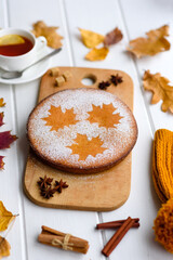 Beautiful fresh sweet pumpkin cake with a maple leaf pattern on a white wooden background