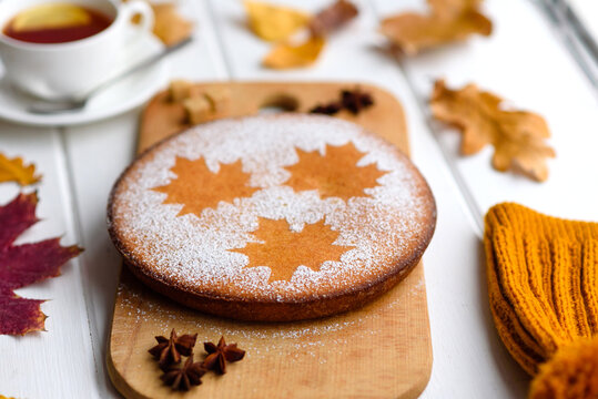Beautiful fresh sweet pumpkin cake with a maple leaf pattern on a white wooden background