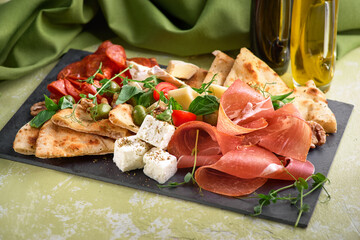 Antipasto platter with ham, prosciutto, salami, blue cheese, mozzarella with pesto and olives
