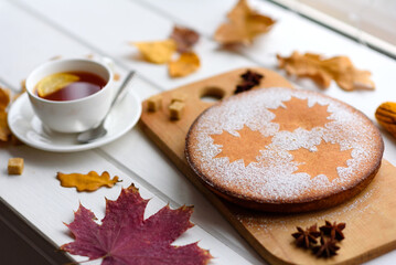 Obraz na płótnie Canvas Beautiful fresh sweet pumpkin cake with a maple leaf pattern on a white wooden background