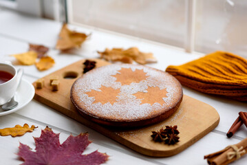 Beautiful fresh sweet pumpkin cake with a maple leaf pattern on a white wooden background