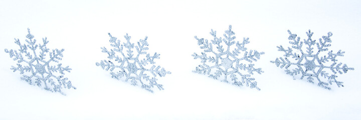 A row of snowflakes in the snow. Christmas snowy background with a bunch of snowflakes. Christmas panoramic background.