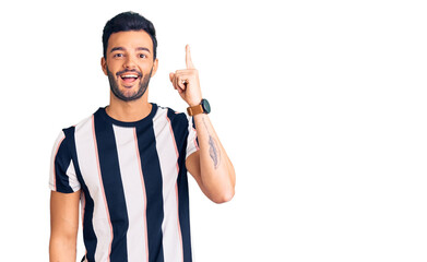Fototapeta premium Young handsome hispanic man wearing striped tshirt pointing finger up with successful idea. exited and happy. number one.