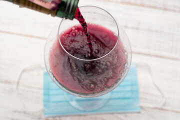A glass of wine and a medical mask. Lockdown coronavirus concept.
