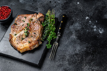Grilled pork loin steak on a marble board. Black background. Top view. Copy space