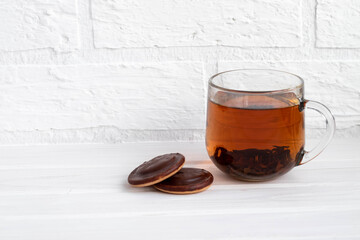a Cup of black tea on a white background next to chocolate covered cookies with space for text