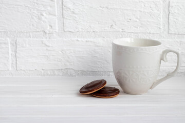 a Cup of black tea white on a white background next to chocolate covered cookies with space for text
