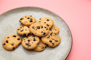 Cookies with chocolate on a plate on a pink background.