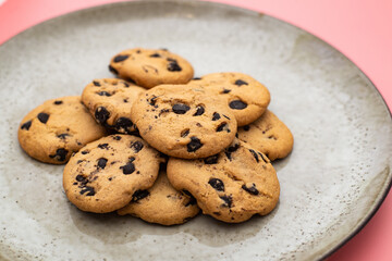 Cookies with chocolate on a plate on a pink background.