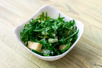Rucolla salad with cheese on a wooden background.