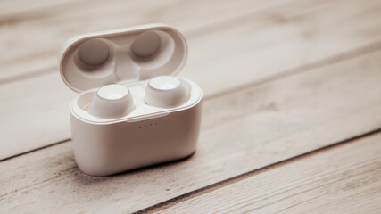 Close up shot of white in-ear true wireless bluetooth headphones earphones with case connection to...