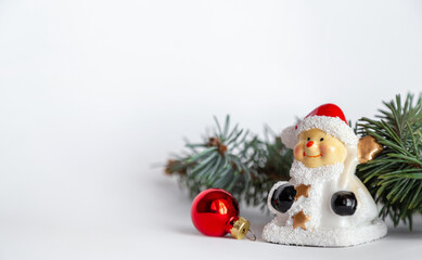 Closeup of Christmas composition of snowman, red ball and fir branch on white background. Merry Christmas card. Winter holiday xmas theme. Happy New Year. Space for text.