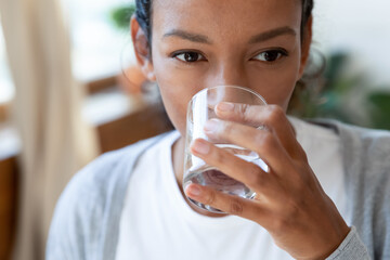 Crop close up of thirsty young biracial woman drink clean clear mineral water from glass....