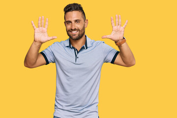 Handsome man with beard wearing casual clothes showing and pointing up with fingers number ten while smiling confident and happy.